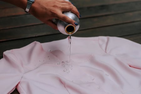 Mulher despejando água sobre um jaleco feito com tecido impermeável.