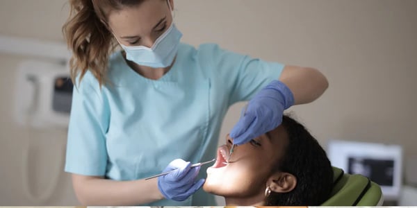 Dentista vestindo uniforme executando procedimento em um paciente.