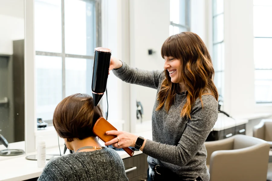 Cabeleireira escovando os cabelos de uma cliente