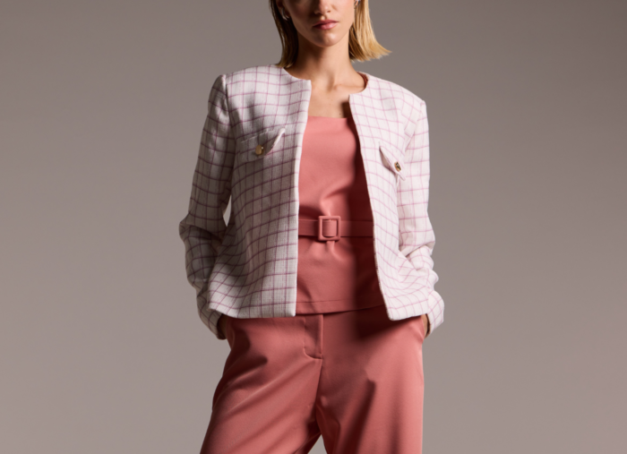 Modelo veste moda modesta com um conjunto monocromático rosa queimado com um blazer de tweed sem gola com estampa xadrez sutil e delicada.