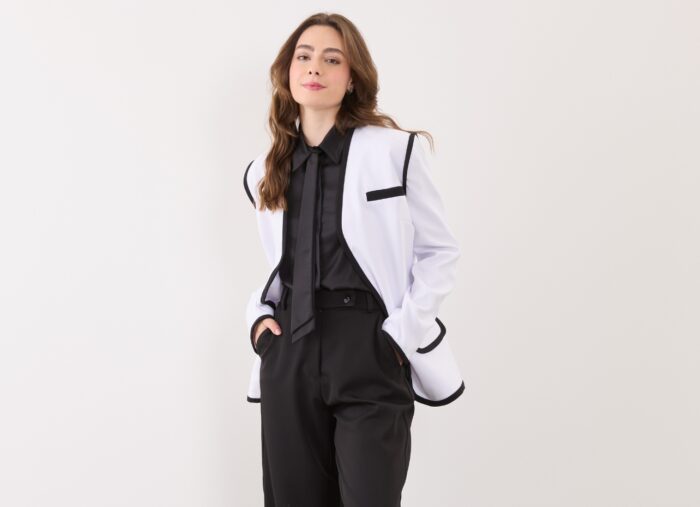 modelo dash veste blazer branco com viés preto e calça social preta representando a alfaiataria feminina