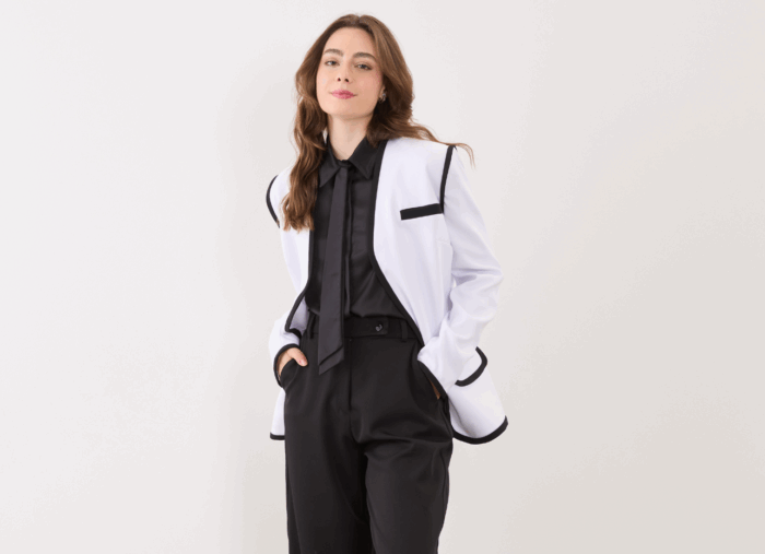 modelo dash veste blazer branco com viés preto e calça social preta representando a alfaiataria feminina